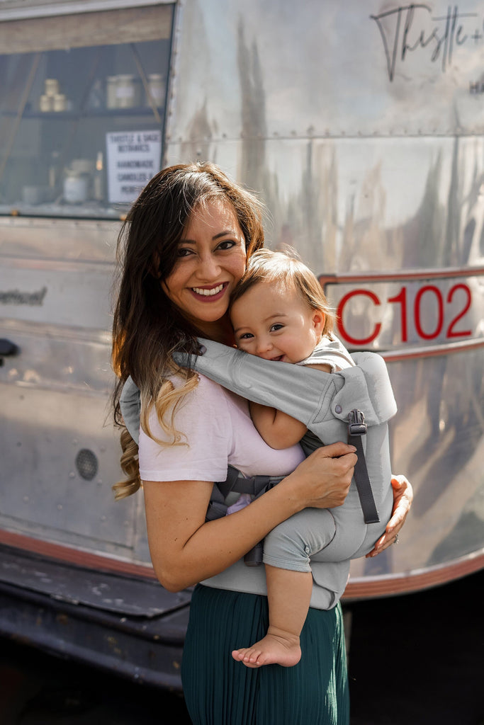 Baby in the Beco Gemini Baby Carrier in grey, front carry position shown