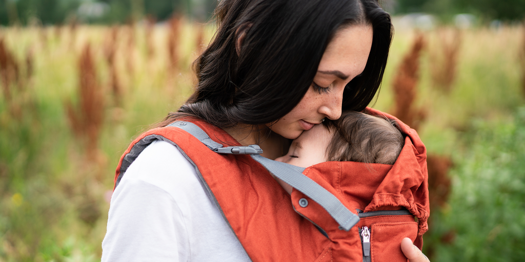 Baby in front carry Beco 8 in rust, with sleep hood up