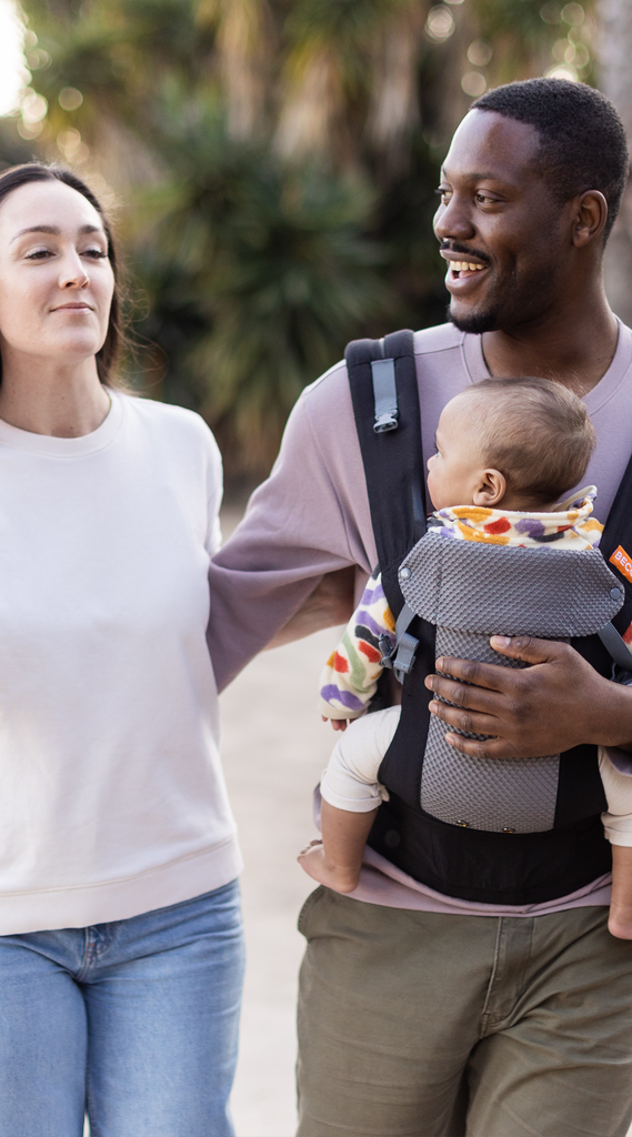 Couple with a baby in a black and grey mesh Beco baby carrier