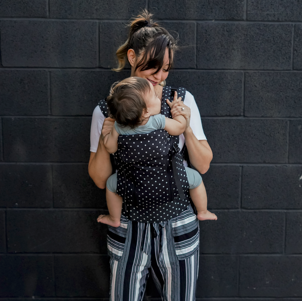 Baby in a Beco 8 baby carrier in black with white polka dots