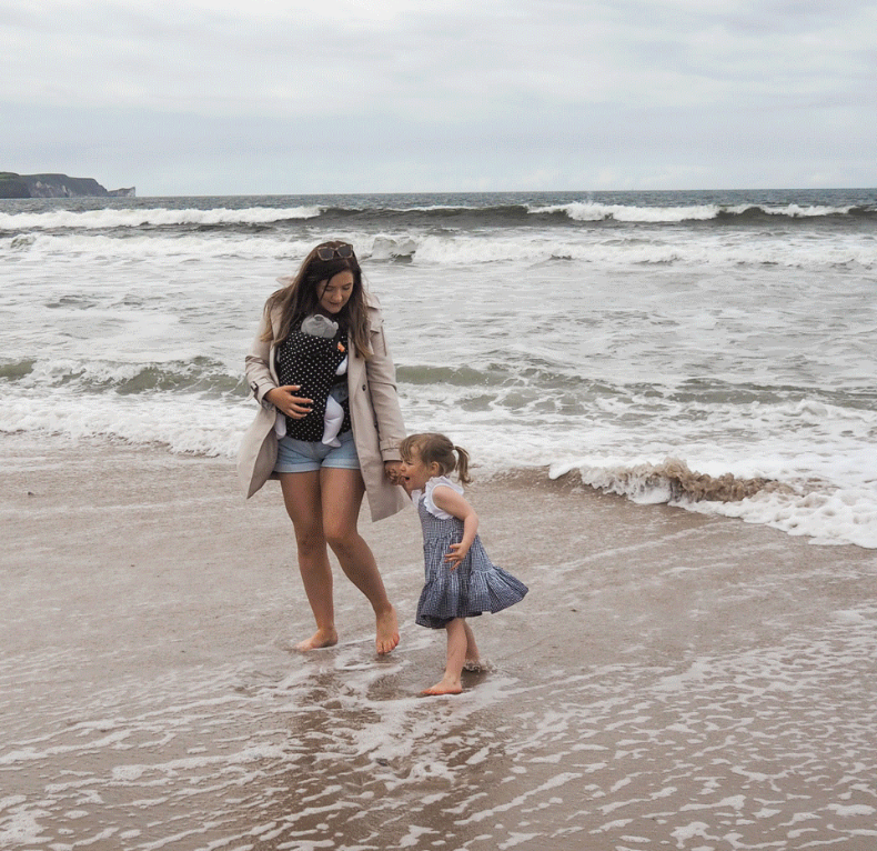 Reviewer on the beach with a baby in spotty Beco carrier