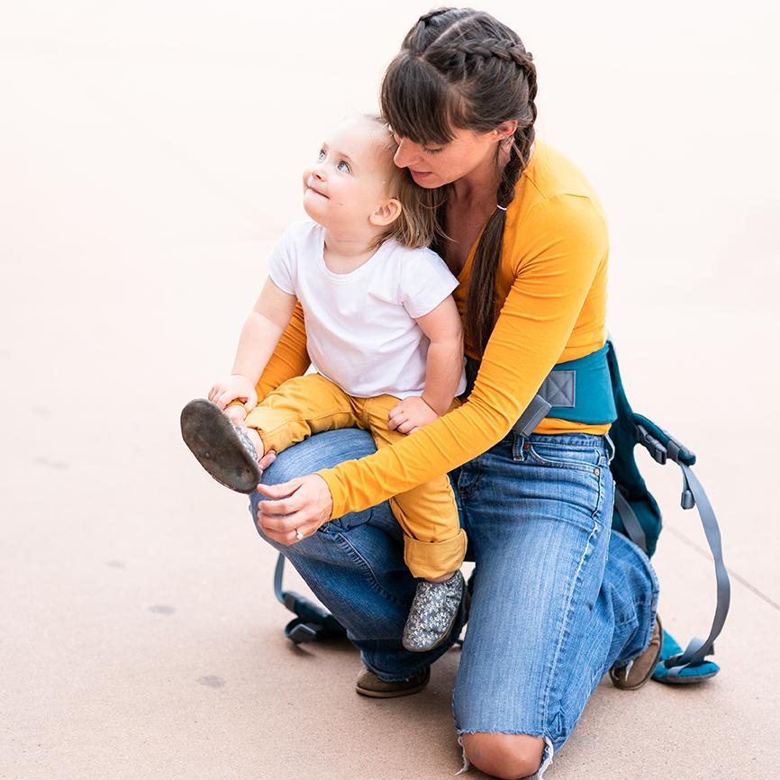 Parent kneeling down with carrier off attending to child