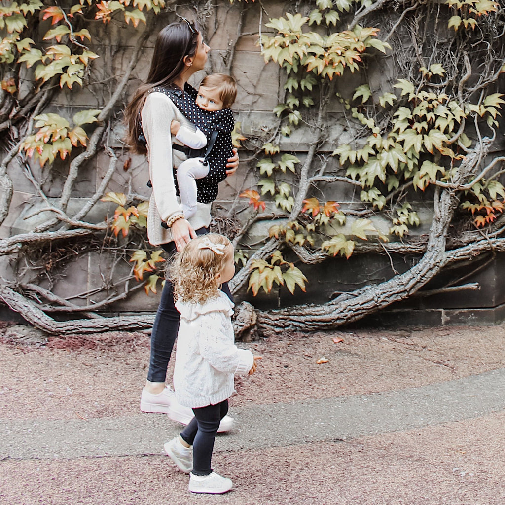 Baby in a front carry Beco baby carrier with white dots