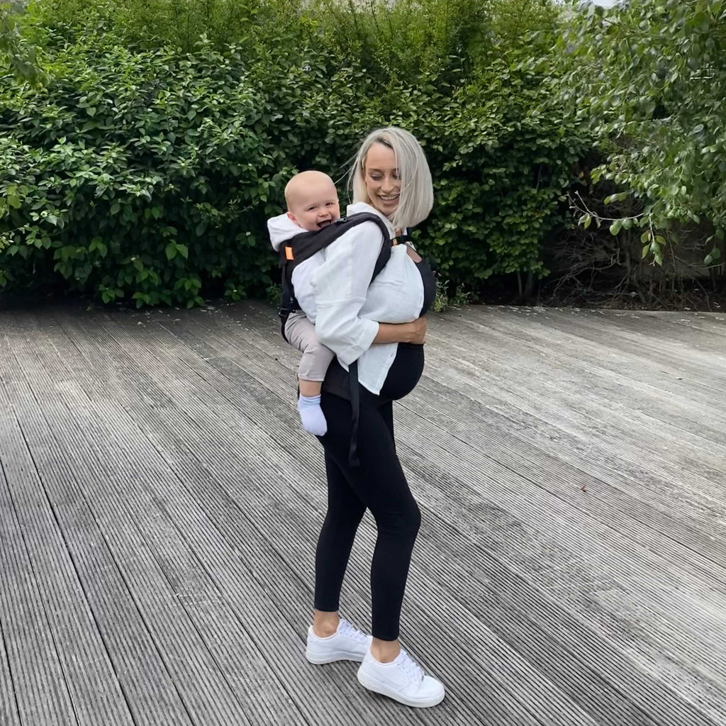 Mum wearing a baby on her back in a black Beco carrier