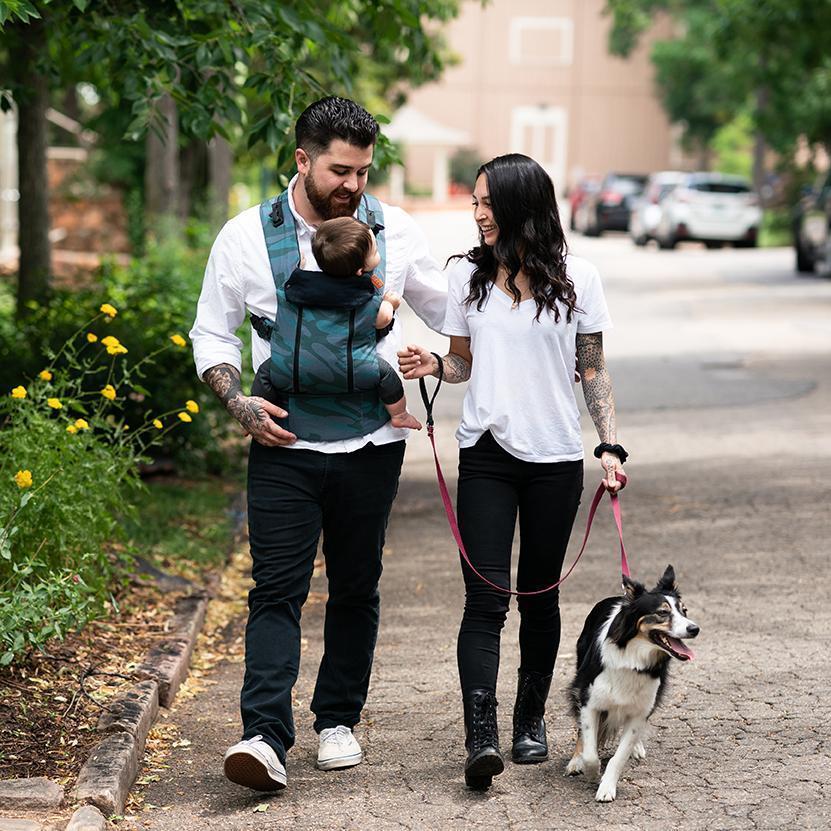 Parent on the move with the blue toned camo print Beco 8 carrier with child in front carry facing in position